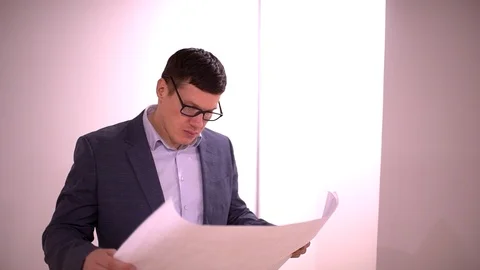 Male Architect In Modern Empty Office Looking At Plans. Happy male architect Stock Footage 87200722