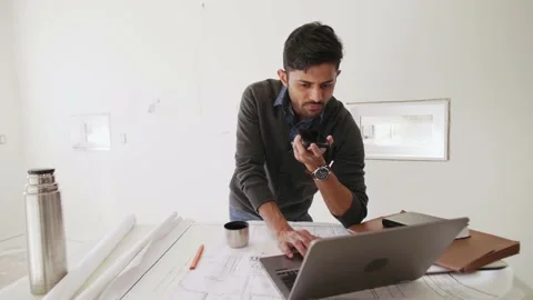 Male architect with smart phone and laptop at home construction site Stock Footage 221041663