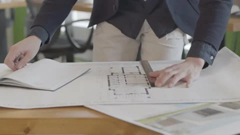 A male architect is studying a building plan in the design office. Video stock 132986516