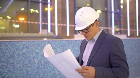 Male architector looking at the plan of building under construction. Young Stock Footage 87188634