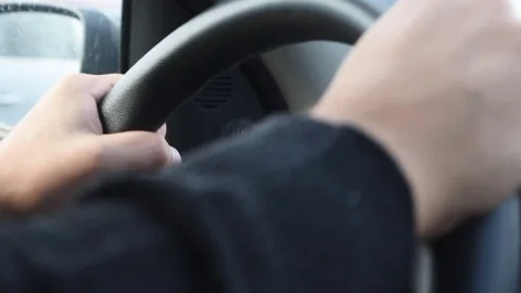 Male arms on a steering wheel while he drives a car Stock Footage 77138235