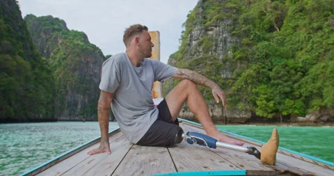 Male with artificial bionic leg sitting on boat front seeing beautiful seascape. Stock Footage 242444482