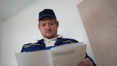 A male assembler in unifrom and a cap is studying the instructions Stock Footage 180537643