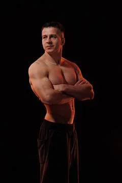 Male athlete bodybuilder posing on a orange light Foto stock