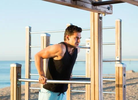 Male athlete doing dips on parallel bars Stock Photos