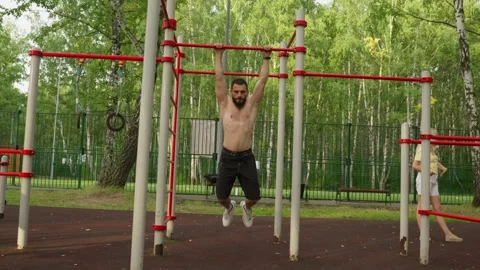 Male athlete executes controlled pullups on colored bars outdoors Vidéo 331366242