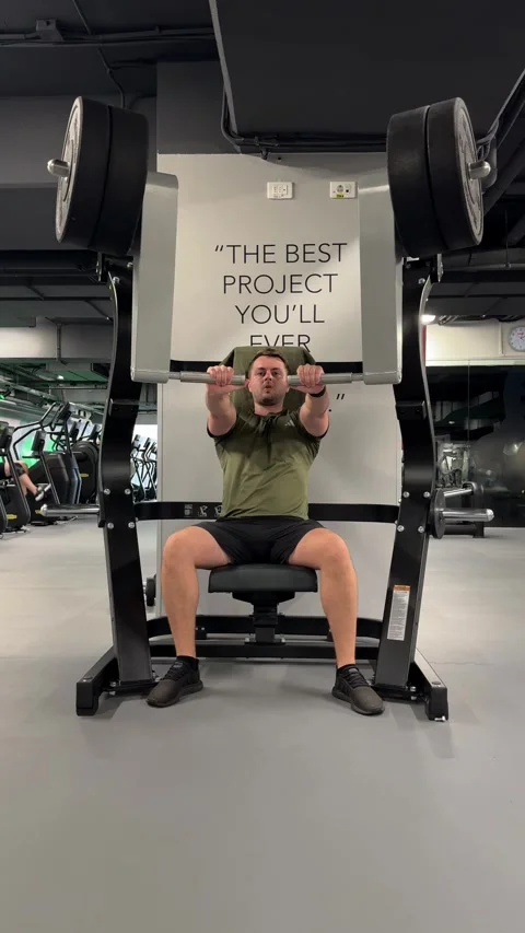 Male athlete performing a chest press exercise on a weight machine in a gym Stock Footage 339601034