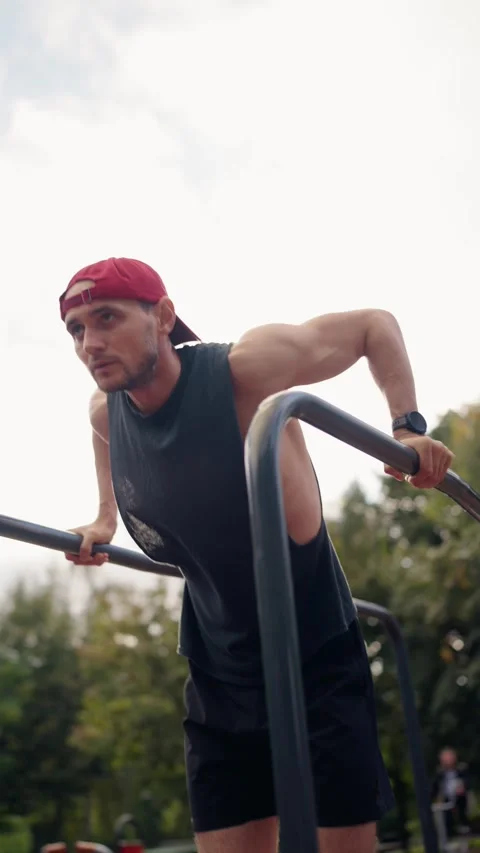 Male Athlete Performing Dips on Parallel Bars in an Urban Park Stock-Footage 310683261
