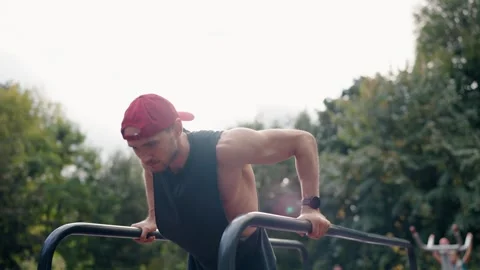 Male Athlete Performing Dips on Parallel Bars in a Park Stock Footage 314264588