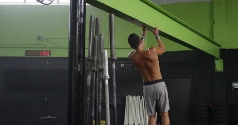 Male athlete performing pull ups on an I-beam in a gym Stock Footage 96899606