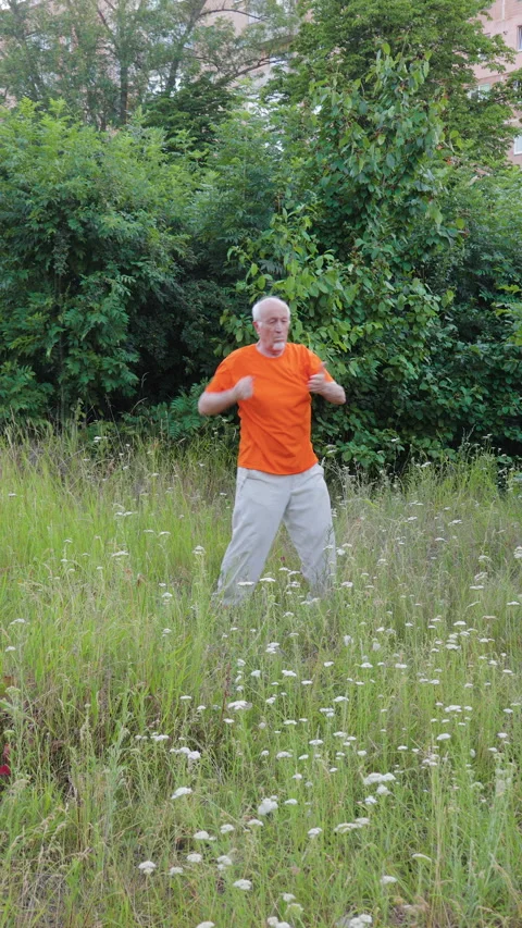 Male athlete performs circular elbow strikes against a natural backdrop Stock Footage 315212962