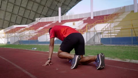Male athlete training in stadium preparing for running Stock Footage 248089136