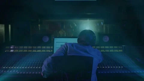 Male audio engineer getting live take cue, tweaking faders, watching animated Stock Footage 332625805