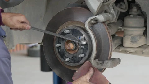 Male auto mechanic using sand paper to clean the car disc break Stock Footage 239743081