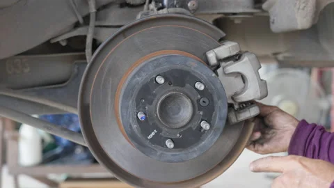 Male auto mechanic's hands putting the break shoes back on to the disc break Stock Footage 239744853
