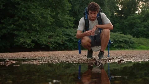 Male Backpacker Crouching by River Examining Rocks - New England Stock Footage 346803300