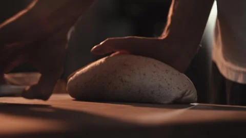 Male baker hands shaping fresh bread dough on rustic wooden table, preparing Stock Footage 344094038