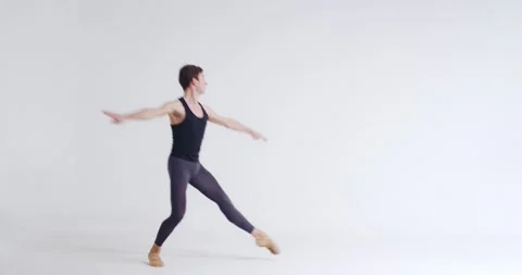 Male ballet dancer performs acrobatic elements of a ballet dance on a white Stock Footage 143238600