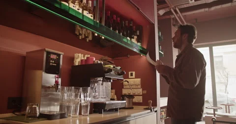 Male barkeeper checking quantity of alcohol bottles on shelves Stock Footage 239169454