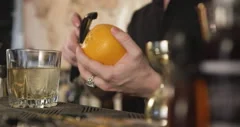 Bartender peels orange peel for cocktail at bar Stock Photo by