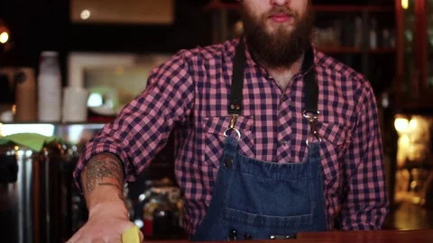 Male bartender putting empty cocktail glass on bar counter after wiping it clean Stock Footage 103803879