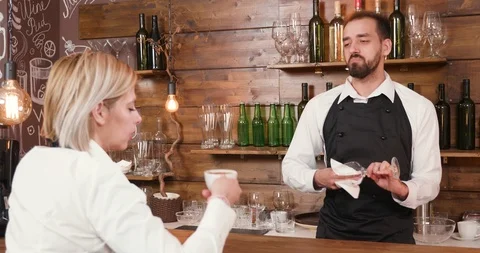 Male bartender talks to the waitress while cleaning a glass Stock Footage 104862385