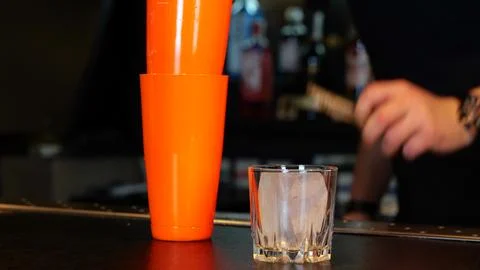 Male bartender working in a bar while making cocktail. Bartender putting a piece 스톡 사진