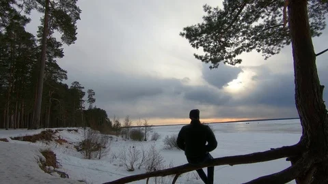 Male in baseball cap sitting by the river in the evening Stock Footage 87467929