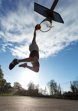 Male basketball player slam dunking Stock Photos