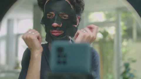 Male Beauty Vlogger Using Sheet Mask while Going Live Stock Footage 233079280