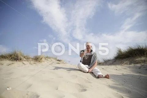 Male best ager sitting in the dunes at the north sea in de haan, belgium, eur Stock Photos