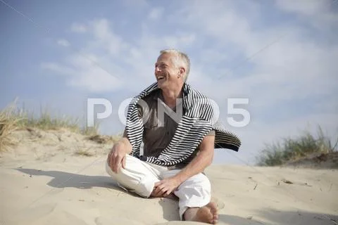 Male best ager sitting in the dunes at the north sea in de haan, belgium, eur Stock Photos