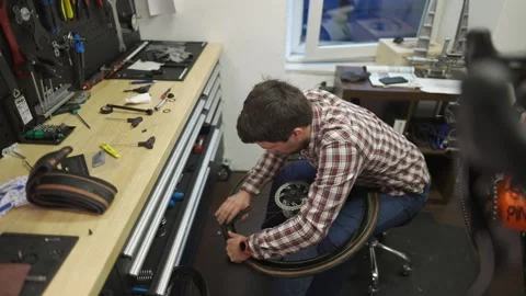 Male bicycle mechanic working in workshop. Bike repairman changing tire on Stock Footage 255842737