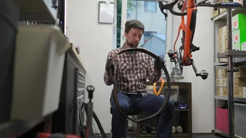 Male bicycle mechanic working in workshop. Bike repairman changing tire on Stock Footage 255842746