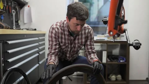 Male bicycle mechanic working in workshop. Bike repairman changing tire on Stock Footage 255842802