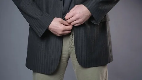 Male in black jacket pulling his pants zipper, embarrassment, man's health Stock Footage 72976474