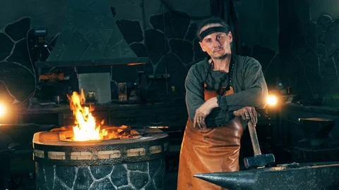 Male blacksmith is standing in a functioning smithy Video stock 111909835