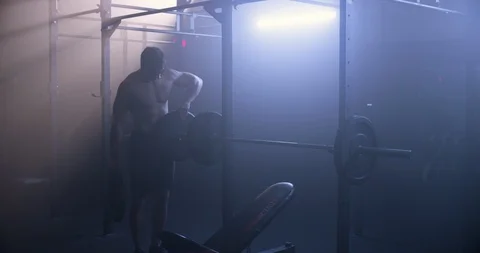 Male bodybuilder adding weight to a barbell Stock Footage 104002983