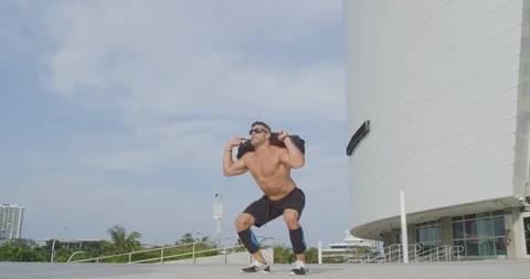 Male bodybuilder training with a sandbag outside Видео 96862053