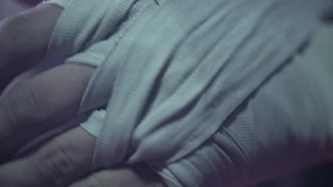 Male boxer wraps his hands with bandages before the fight training. It's a dark Stock Footage 80862000