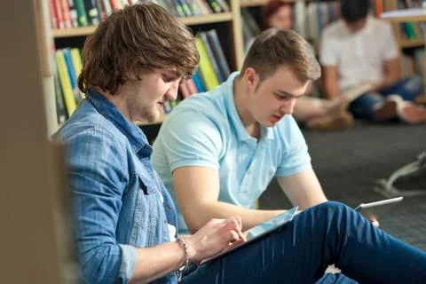 Male boy students using tablet computers in library Stock Photos