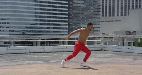 Male break dancer performing flips on top of a parking garage Stock Footage 97389070