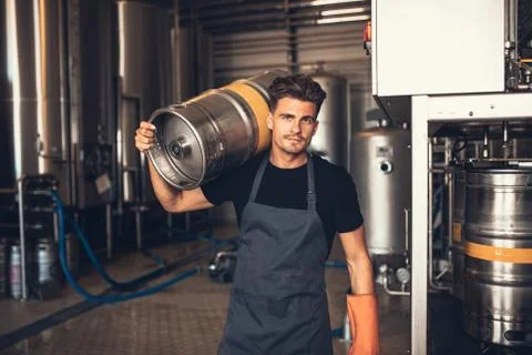 Male brewer carrying metal container at brewery factory Stock Photos