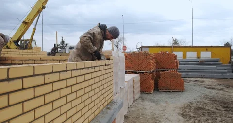 Male bricklayer building flat brick wall, construction team, work, construction 動画素材 129837932