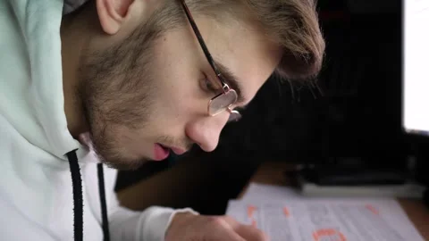 Male broker writes data on paper after analyzing foreign exchange graphs Stock Footage 309299770