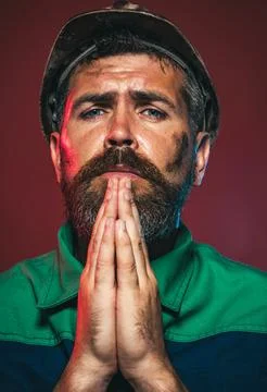 Male builder, architect or engineer in protective hard hat praying. Mechanica Stock Photos