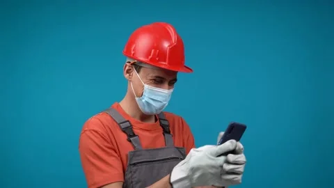 Male builder in face mask browsing social media on smartphone Vídeo Stock 191896552