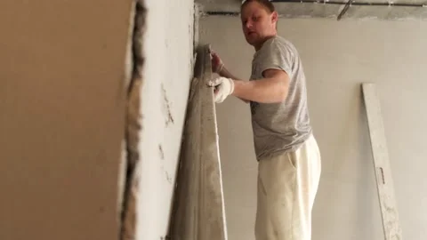 Male Builder Levels Plaster On Wall. Smooth Board. Removes Extra Layer. Putty Stock Footage 168355546