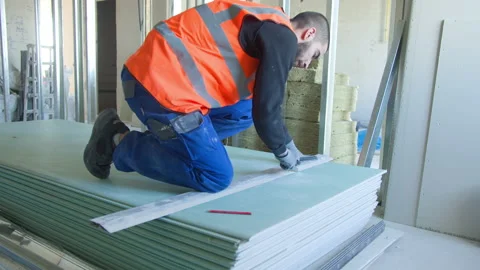 Male builder measuring and cutting gypsum panel Stock Footage 154395057