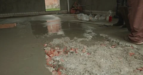 Male builder pouring wet cement mixture from a bucket to create a concrete floor Stock Footage 338244262